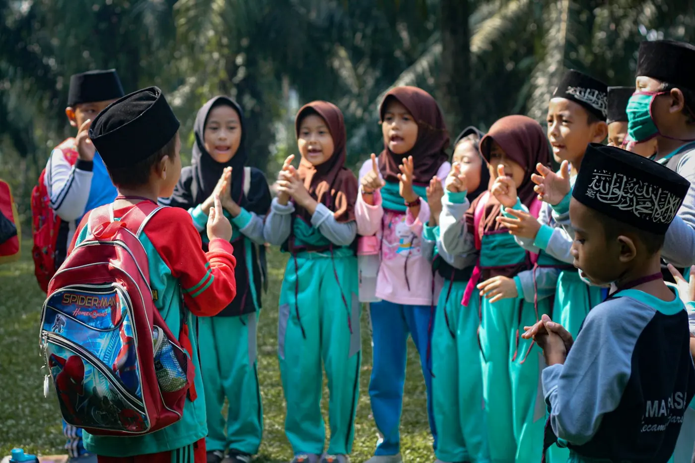 Anak-anak sekolah berhijab dan berpeci bertepuk tangan bersama