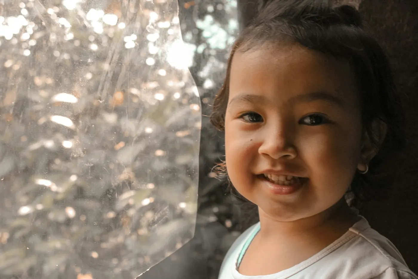 Anak perempuan tersenyum di bawah pohon